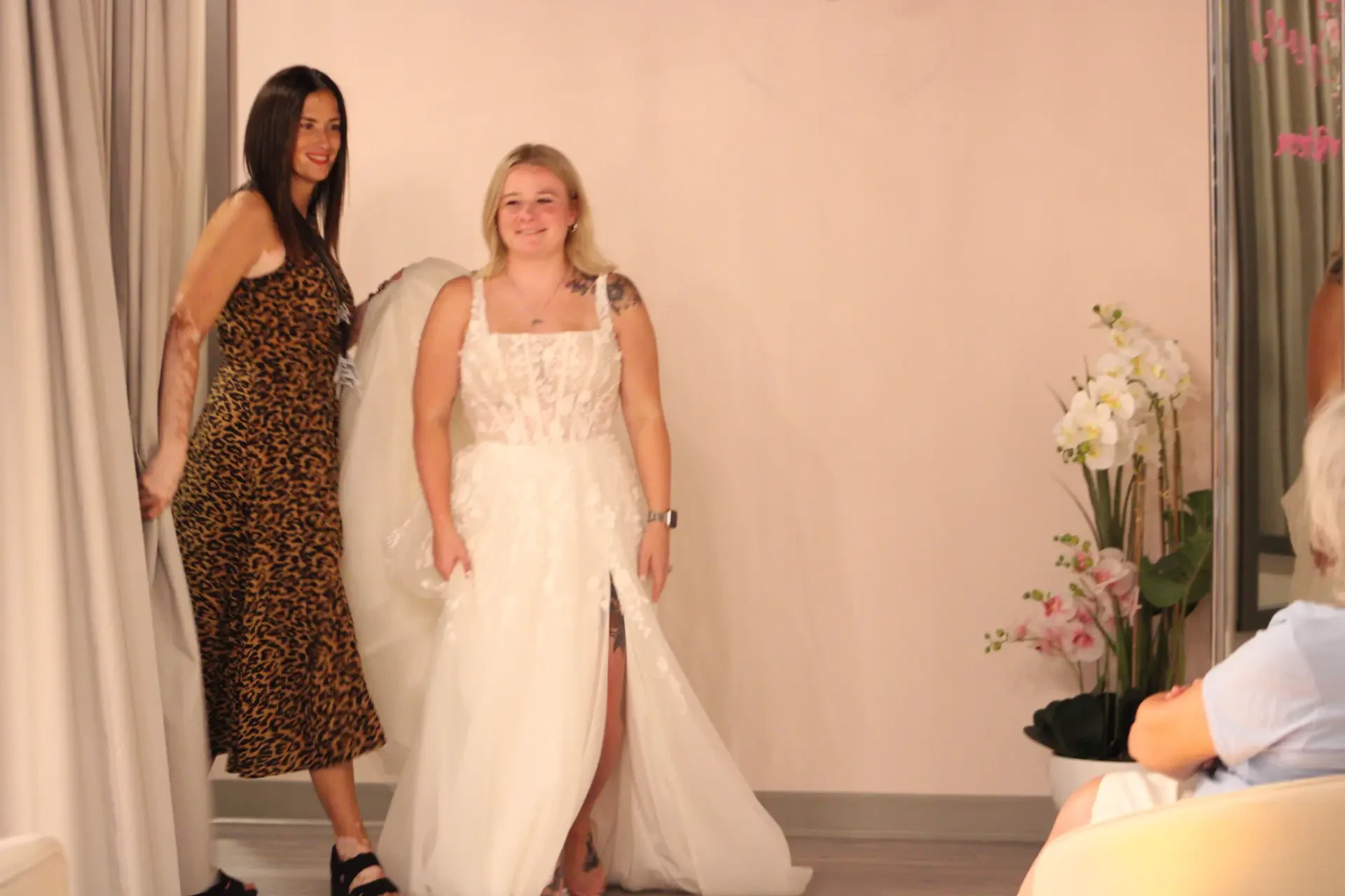 woman is wearing a square neckline sleeveless wedding dress in a dressing room at a bridal boutique