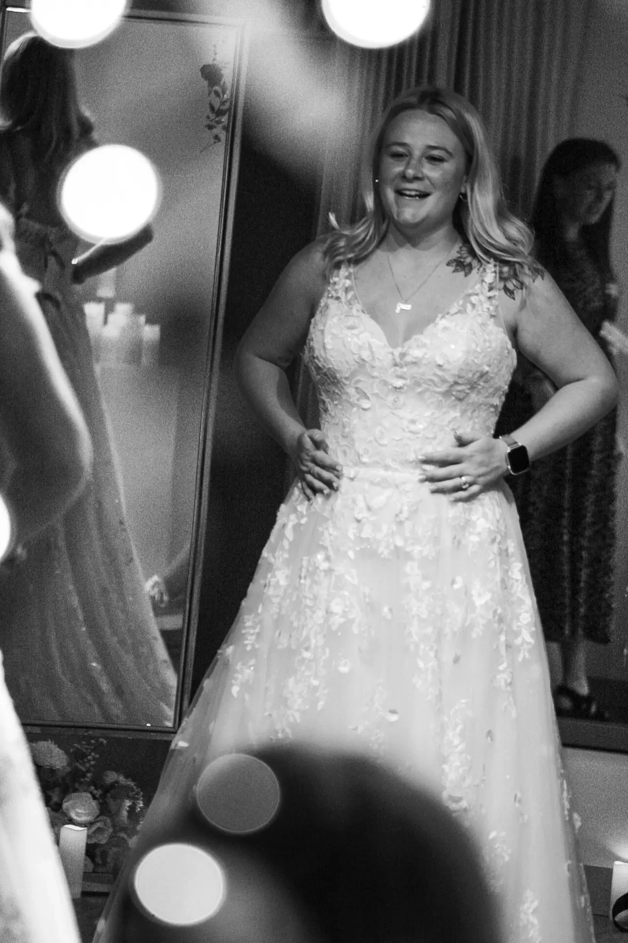 image shows a women excitedly trying on a sleeveless a-line bridal gown