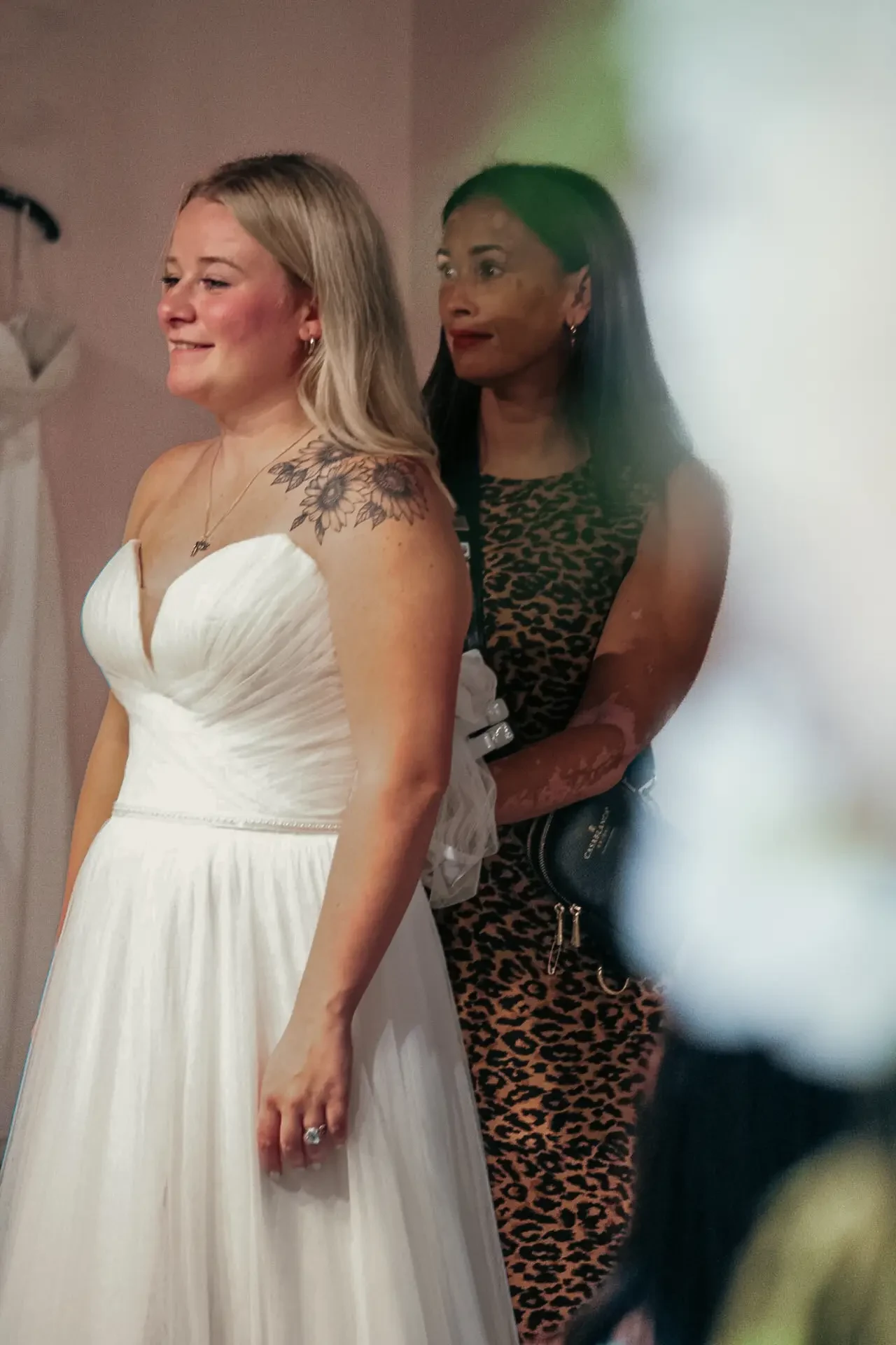 image shows a women trying a strapless wedding gown while a woman stands behind her