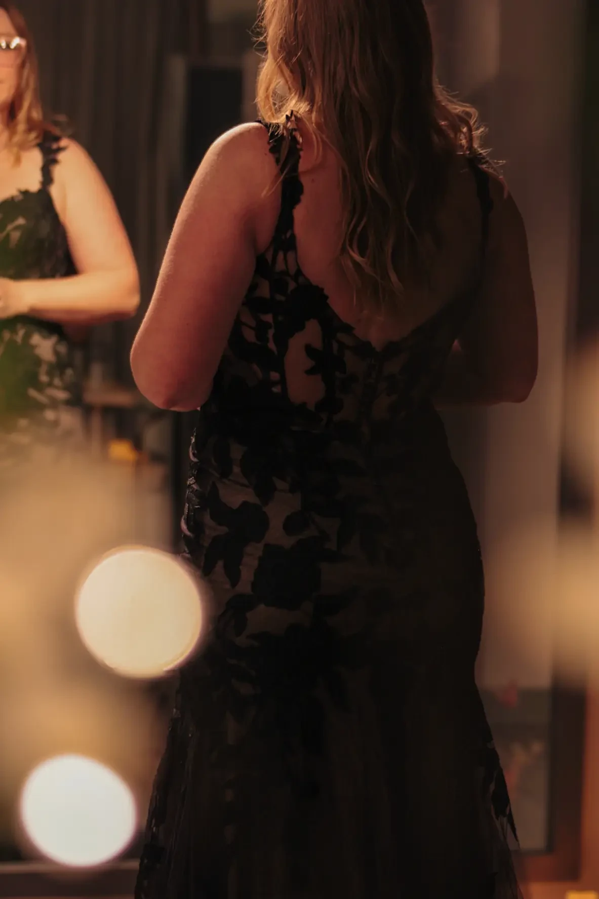 bride is wearing a sleeveless open back lace black wedding gown