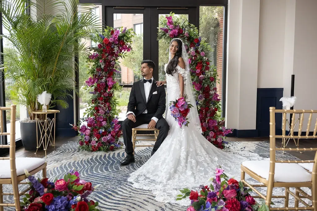 image shows two models, one wearing a wedding dress and one wearing a tuxedo, in a beautiful setting
