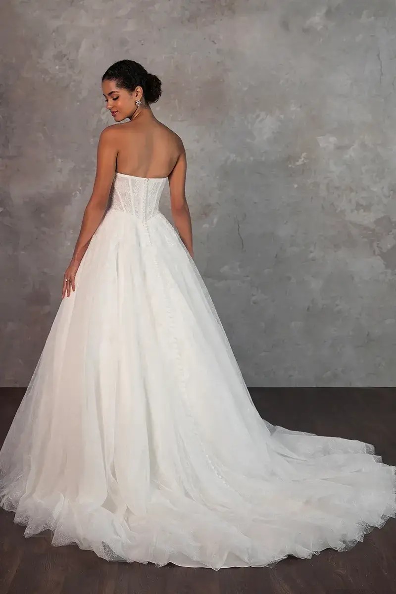 Model is wearing a strapless ball gown with a corset bodice and long train