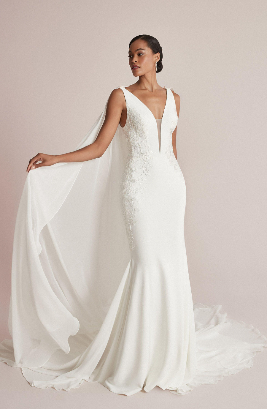 model is wearing a sleek sleeveless wedding dress inspired by the maturity of the evermore era by taylor swift