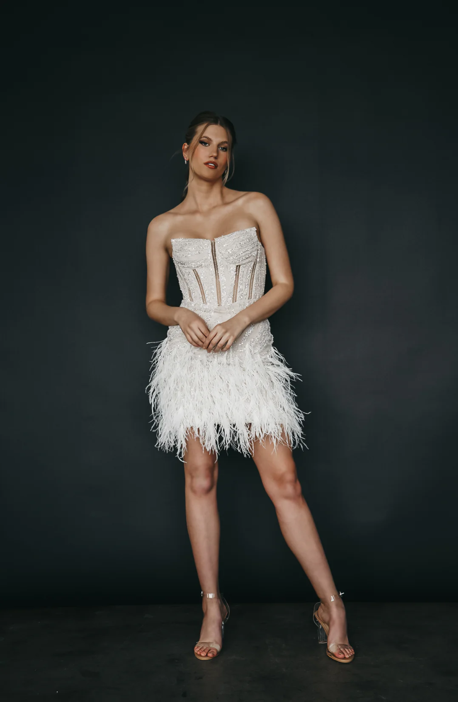 model is wearing a mini feather wedding dress inspired by taylor swift's fearless era