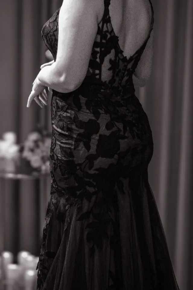 bride is wearing a sleeveless open back lace black wedding gown