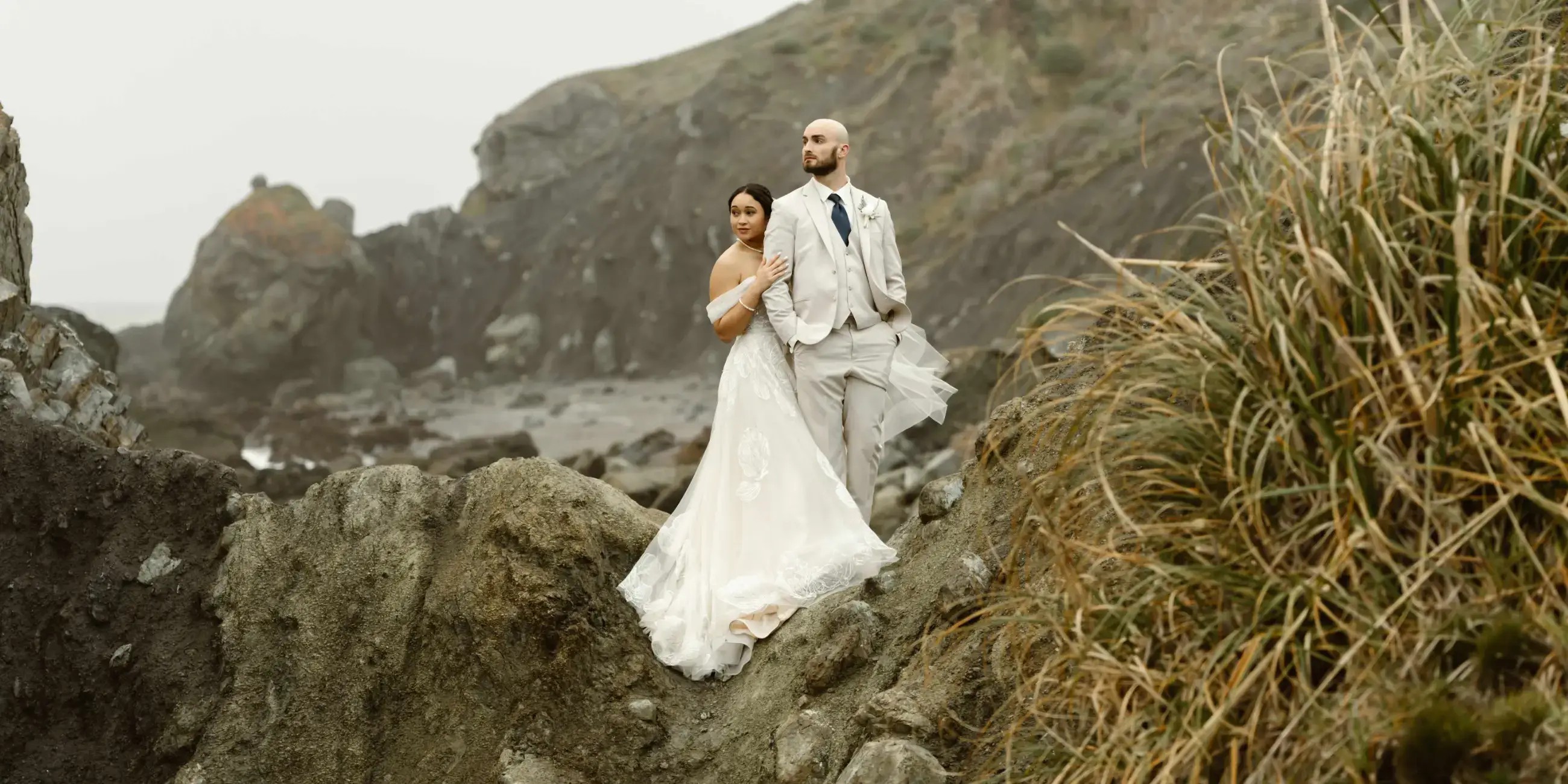 image shows a bride and her husband looking off into the distance on their wedding day