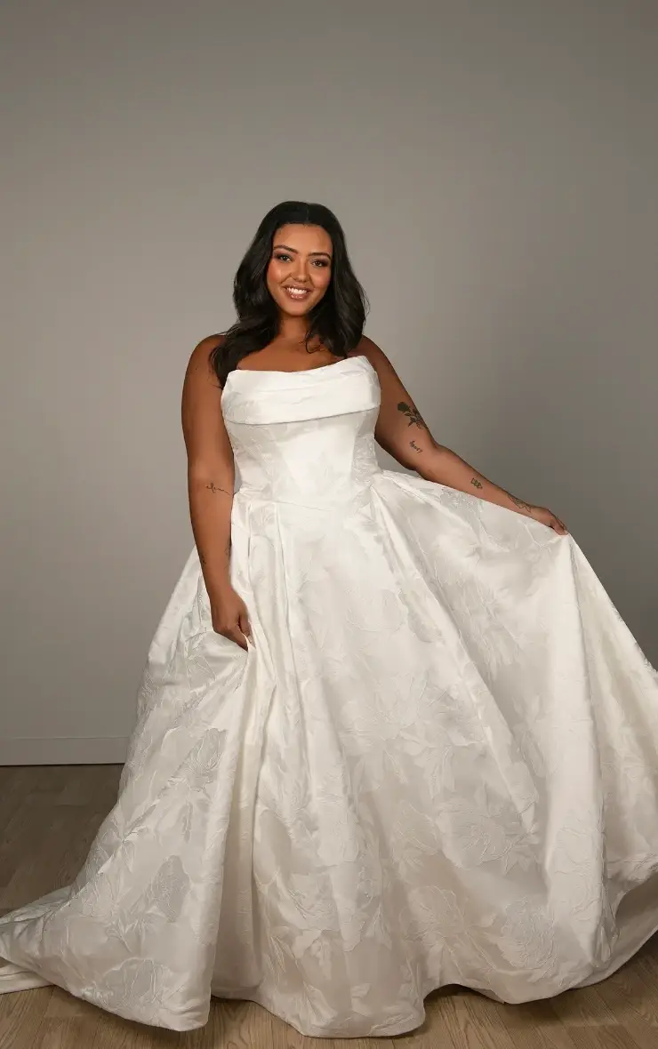 Model is wearing a strapless satin ballgown with a ruched neckline, Basque waist, and a pleated skirt made for fairytale winter celebrations.