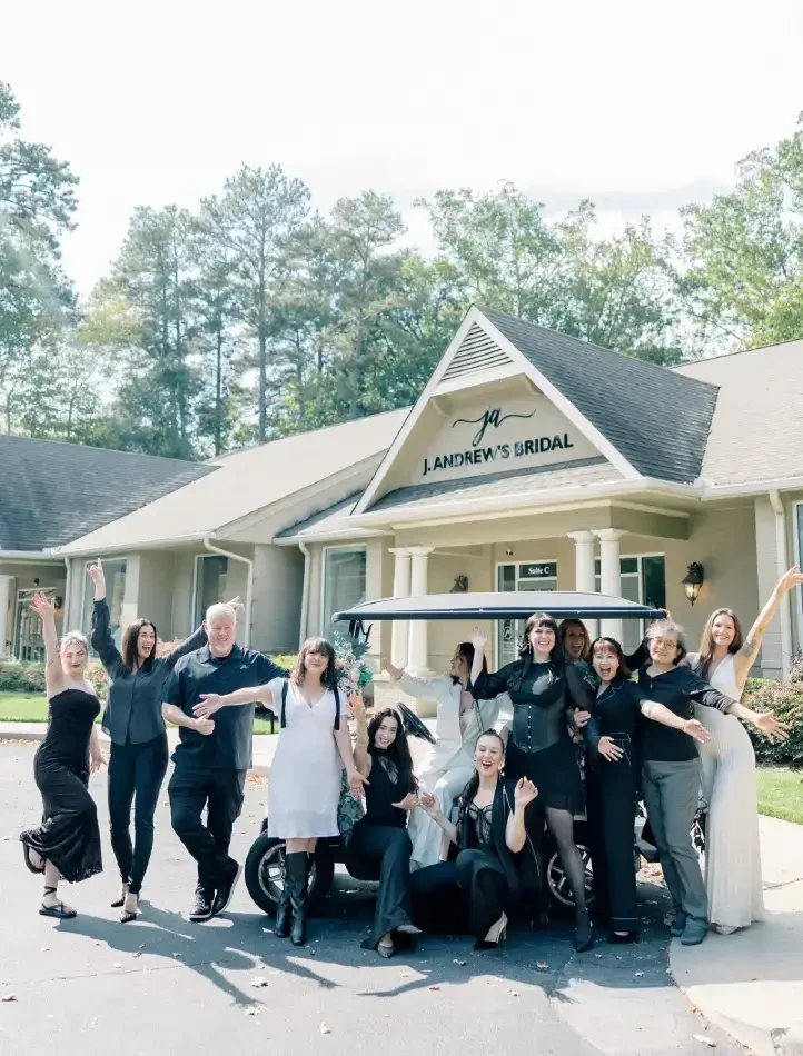 A group of people celebrating outside a bridal shop, posing enthusiastically around a golf cart.